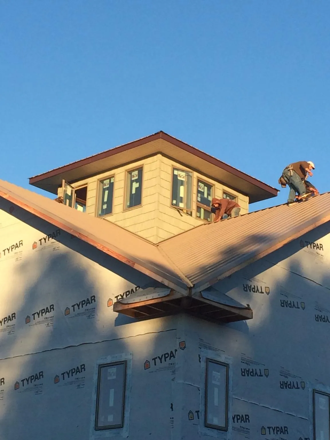 Roofers working around a rooftop cupola on a new metal roof at sunset — Roof Waterproofing in Clark by Roofing Brothers